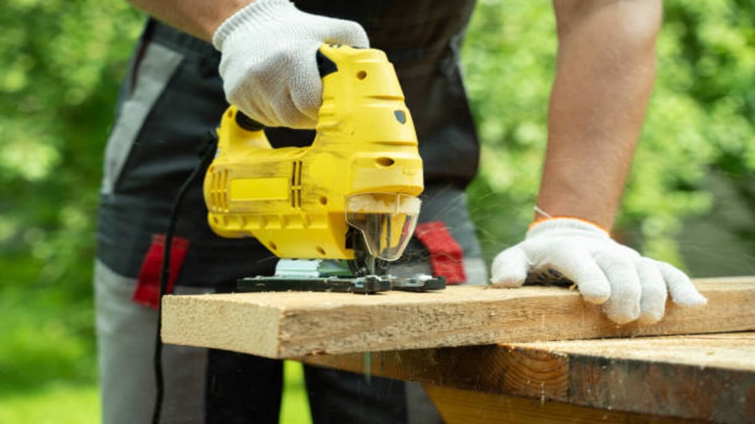 close-up-male-carpenter-cuts-a-wooden-board-using-an-electric-jigsaw