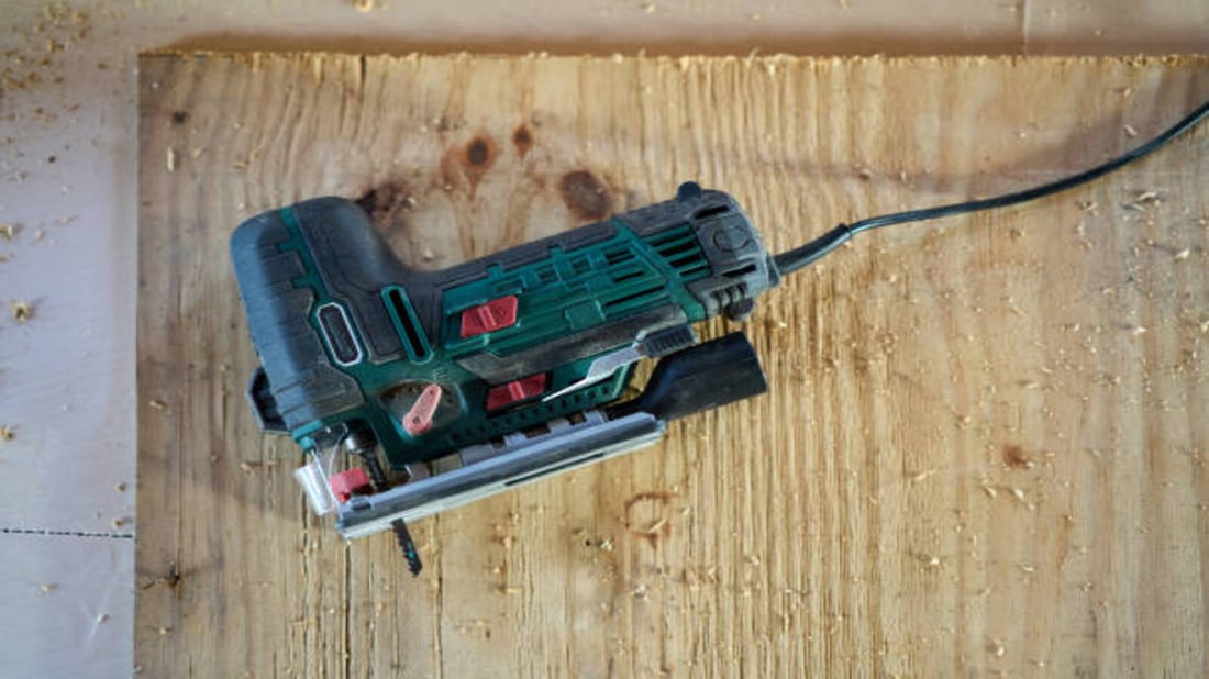 electric-jigsaw-resting-on-wooden-plank-after-cutting-process